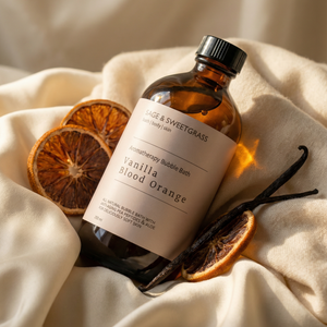 Bottle of Vanilla Blood Orange bath product with dried oranges and vanilla beans on a beige fabric background