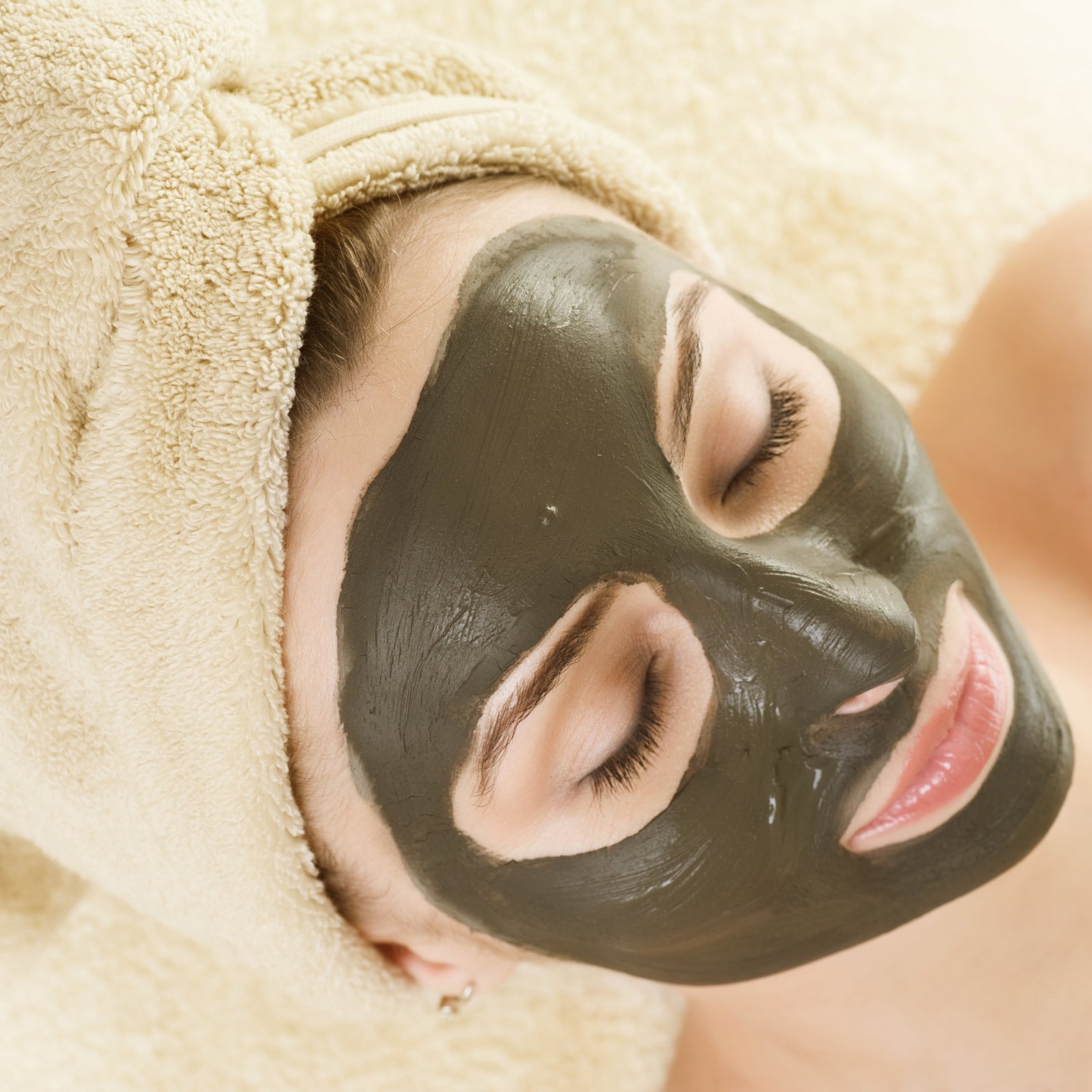 Woman lying down with a mud mask on her face