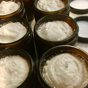 Multiple small brown jars filled with a white powdery substance.