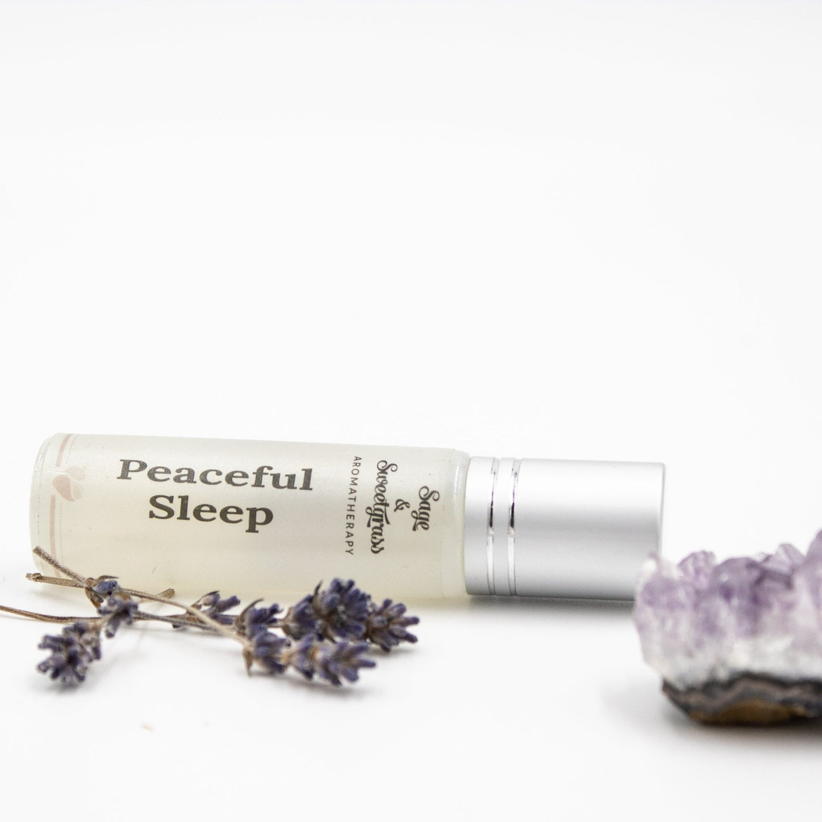 Roll-on bottle labeled 'Peaceful Sleep' with lavender flowers and a crystal on a white background