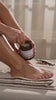 Woman applying sugar scrub to legs and feet in a soft peaceful setting